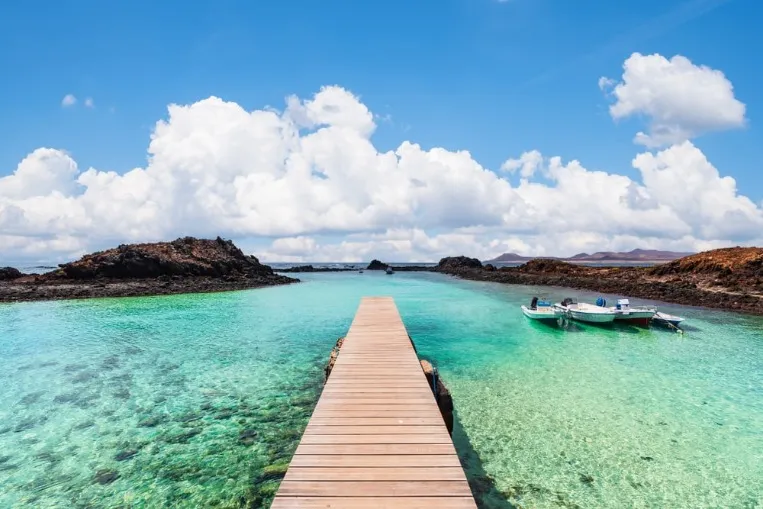 Wooden jetty with a turquoise lagoon and small boats on Isla de Lobos