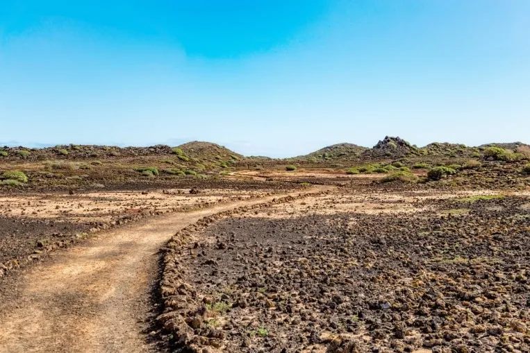 Marked hiking trail through the volcanic landscape of Isla de Lobos
